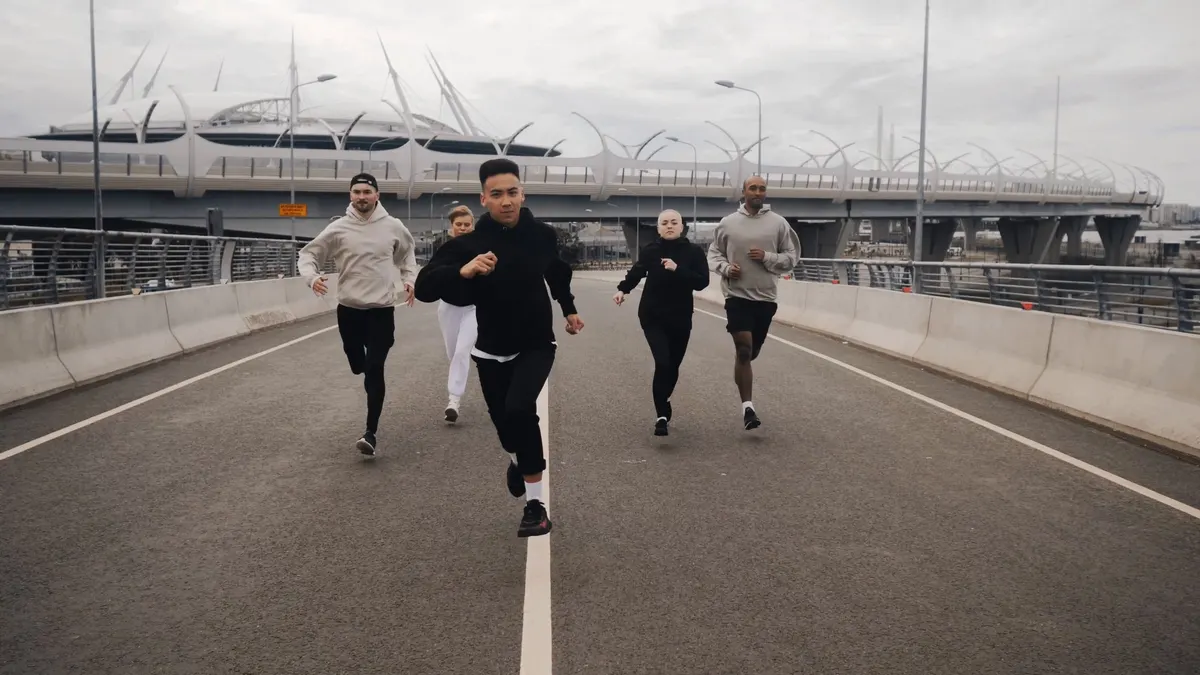 A running crew coming up an empty elevated road under a flat grey sky